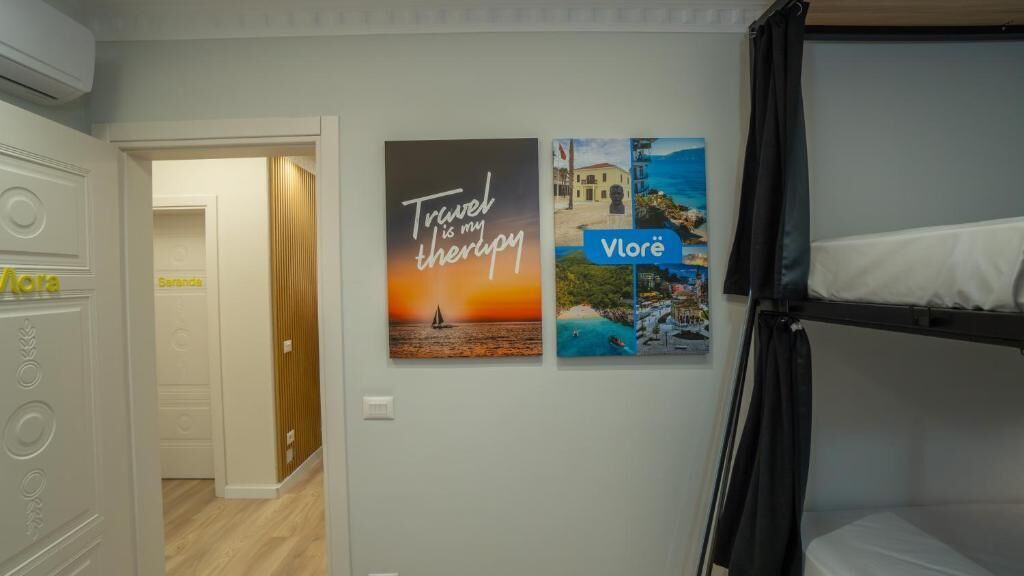 A room with a bunk bed, a door leading to another room, and two framed pictures on the wall.