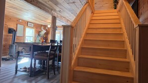 Un escalier en bois mène à un espace repas comprenant une table et des chaises.