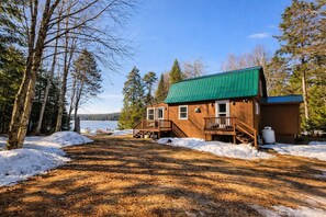 Une cabane dotée d’un toit végétalisé, d’une terrasse en bois et offrant une vue sur un lac.