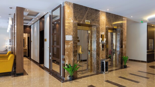 A hotel lobby with a reception desk, a seating area, and a marble wall. - Topaz Hotel Suites (Riyadh)