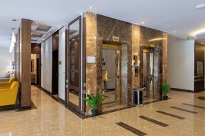 Eine Hotelhalle mit Empfangstresen, einer Sitzecke und einer Marmorwand.