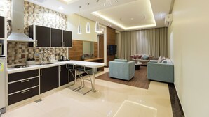 A modern kitchen with a dining area, a sofa, and a TV. - Topaz Hotel Suites (Riyadh)