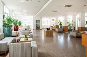 Un vestíbulo amplio con zonas de estar, un mostrador de recepción y grandes ventanales que dejan entrar luz natural.