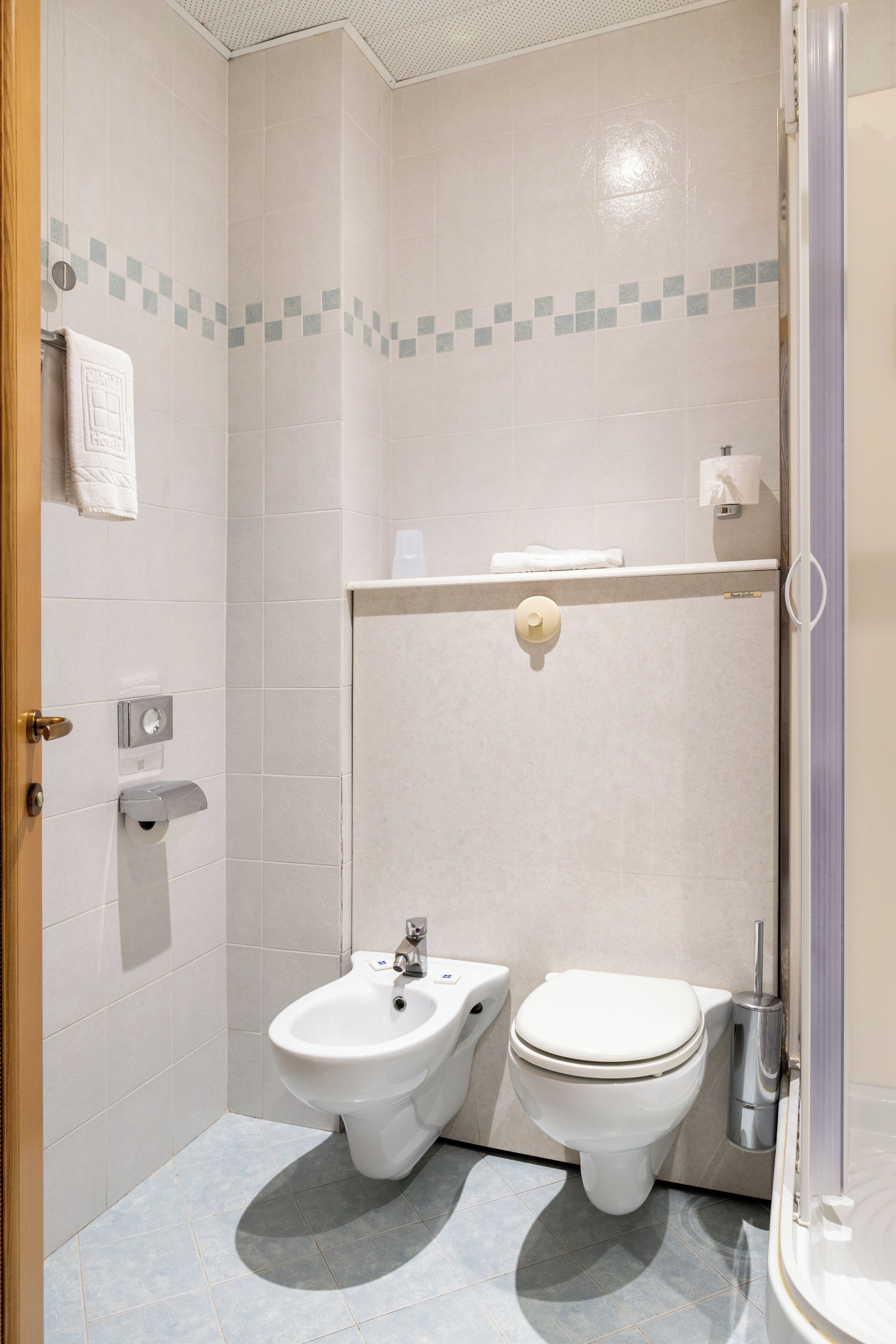 A bathroom with a bidet, toilet, and a towel rack.