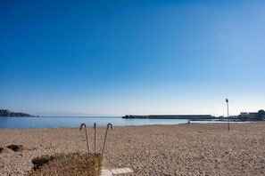 A beach with a clear sky, a calm sea, and a distant rocky coastline. - GuestHost - La Romantica - Lovely Apt with Terrace (Naxos)