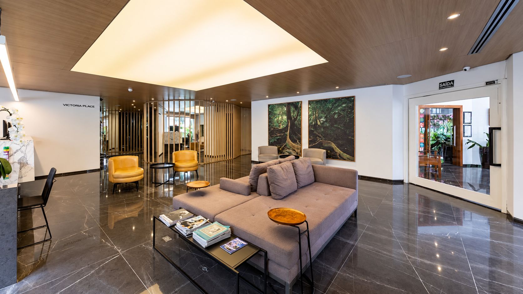 A modern lobby with a sofa, chairs, a reception desk, and a large window.