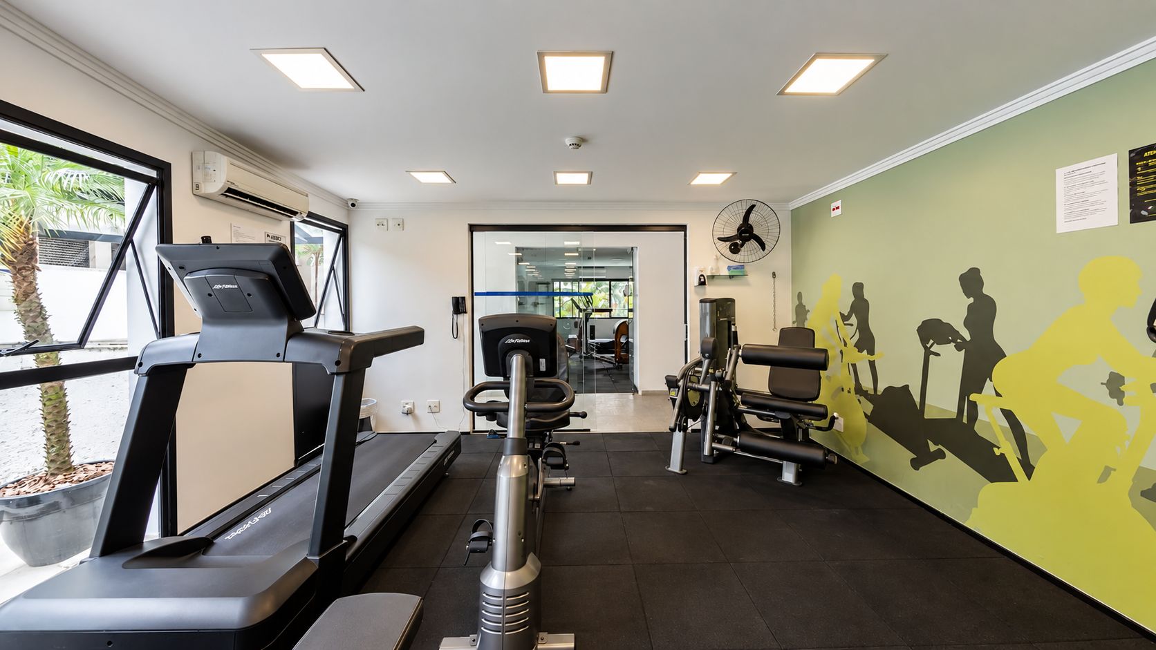 A gym with treadmills, weight machines, and a wall mural.