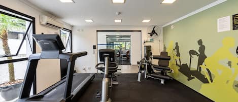 A gym with treadmills, weight machines, and a wall mural.