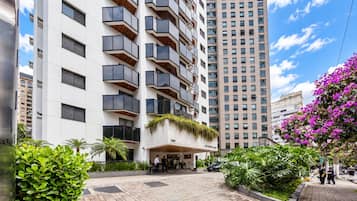Een modern hotel met een opvallende ingang, meerdere balkons en weelderige begroeiing.