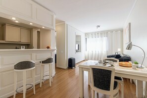 Una cocina moderna con armarios blancos y un comedor con mesa y taburetes.