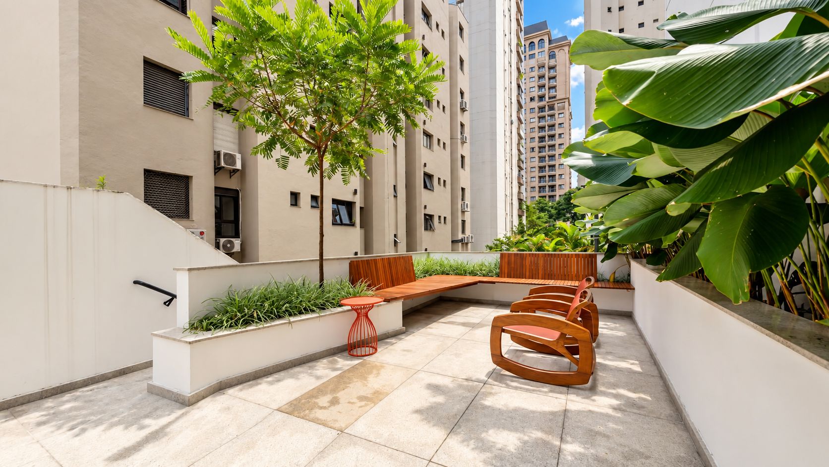A rooftop terrace with a seating area, a tree, and a view of high-rise buildings.
