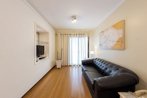 Una sala moderna con un sofá de cuero, un televisor de pantalla plana y un cuadro en la pared.