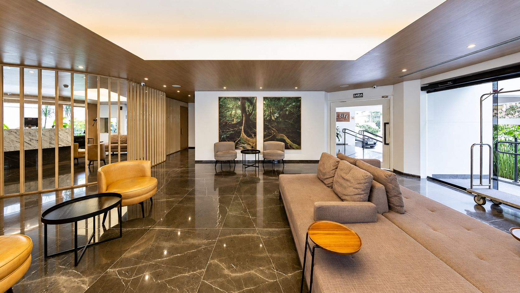 A modern lobby with a sofa, chairs, a coffee table, and a large window.