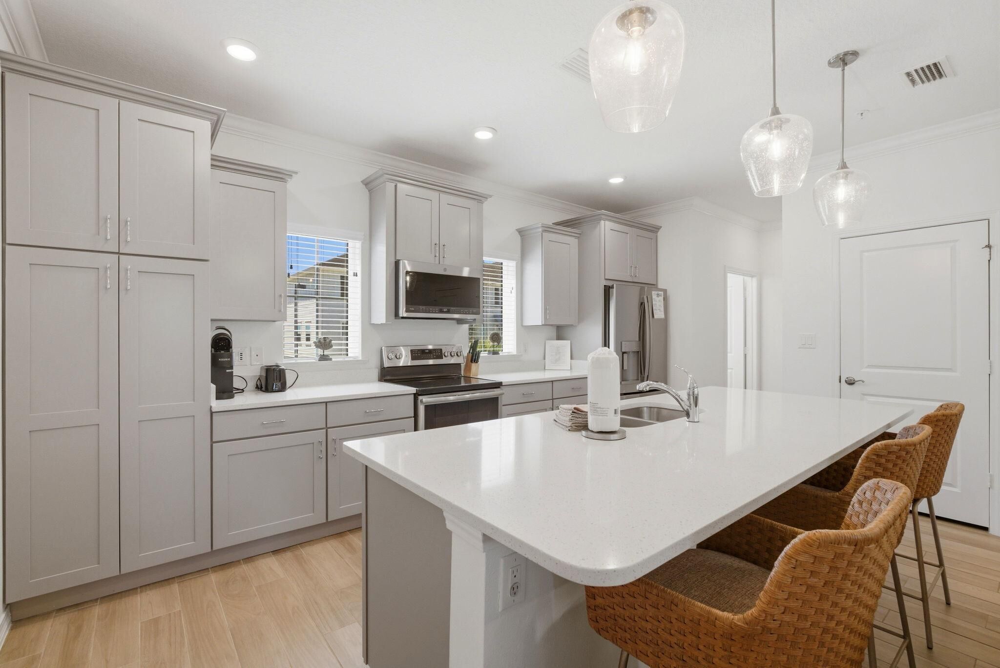A modern kitchen with white cabinetry, stainless steel appliances, and a large island with bar stools.