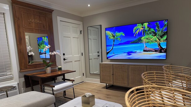 Ein modernes Wohnzimmer mit Flachbildfernseher, Essbereich und Sitzecke mit Korbmöbeln.