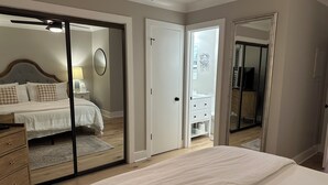 Ein Schlafzimmer mit Bett, Schminktisch, Spiegel und einer Tür zum Badezimmer.