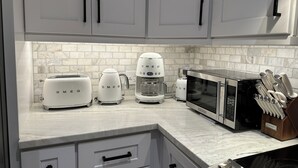 Eine Küche mit weißen Schränken, einem Toaster, einer Kaffeemaschine, einer Mikrowelle und einem Messerblock.