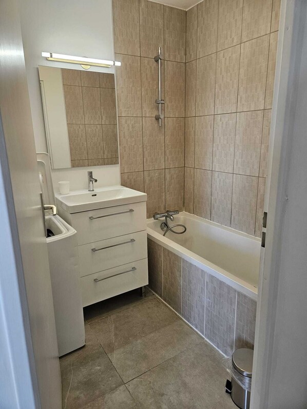 A bathroom with a white sink, mirror, and a bathtub.
