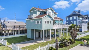 A two-story house with a balcony, a porch, and a fenced yard. - Beachside Vibes (Galveston)
