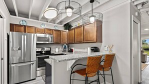 Una cocina moderna con electrodomésticos de acero inoxidable, armarios de madera y encimera de granito.