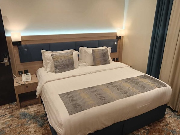 Habitación de hotel con cama, mesitas de noche, teléfono y cabecera.