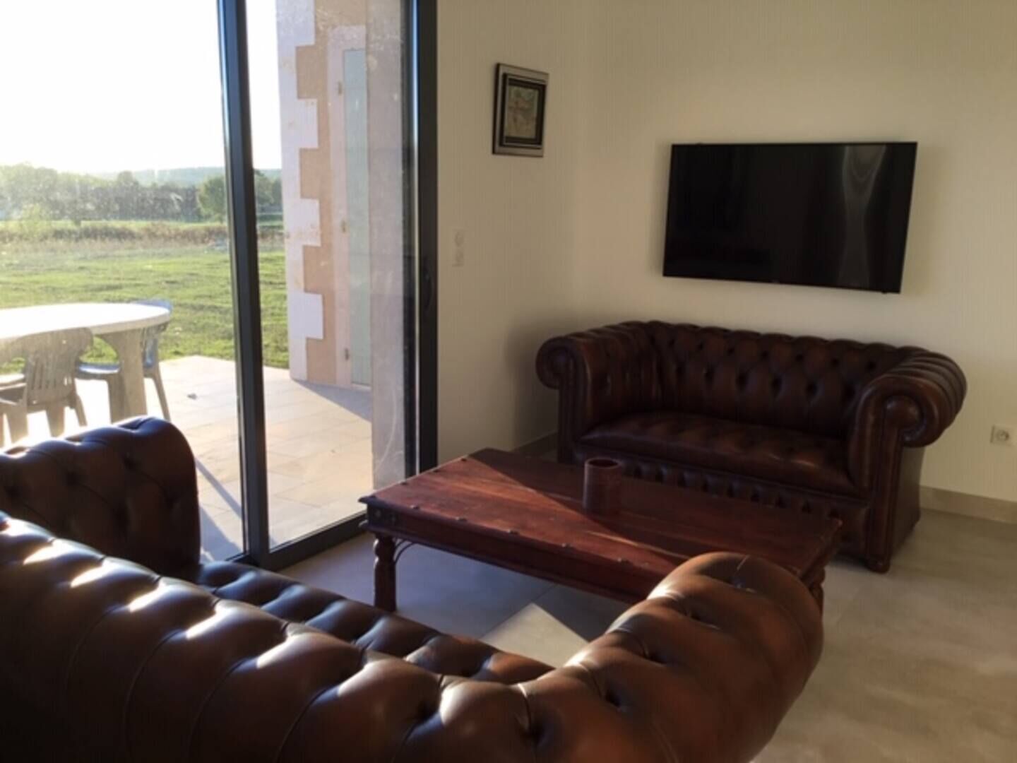 Ein Wohnzimmer mit einer Ledersofa, einem Holztisch und einem flachbildfernseher an der Wand.