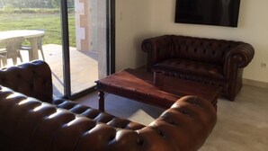 Ein Wohnzimmer mit einer Ledersofa, einem Holztisch und einem flachbildfernseher an der Wand.