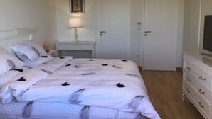 Ein Schlafzimmer mit einem Bett, einem Nachttisch mit Lampe, einem Schminktisch und einer Tür.