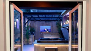 Une terrasse extérieure moderne, dotée d’un jacuzzi, d’un écran de télévision et d’une plateforme en bois.
