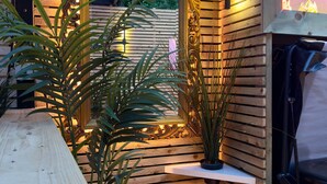 Une cabane en bois avec un grand miroir, des plantes en pot et un banc.