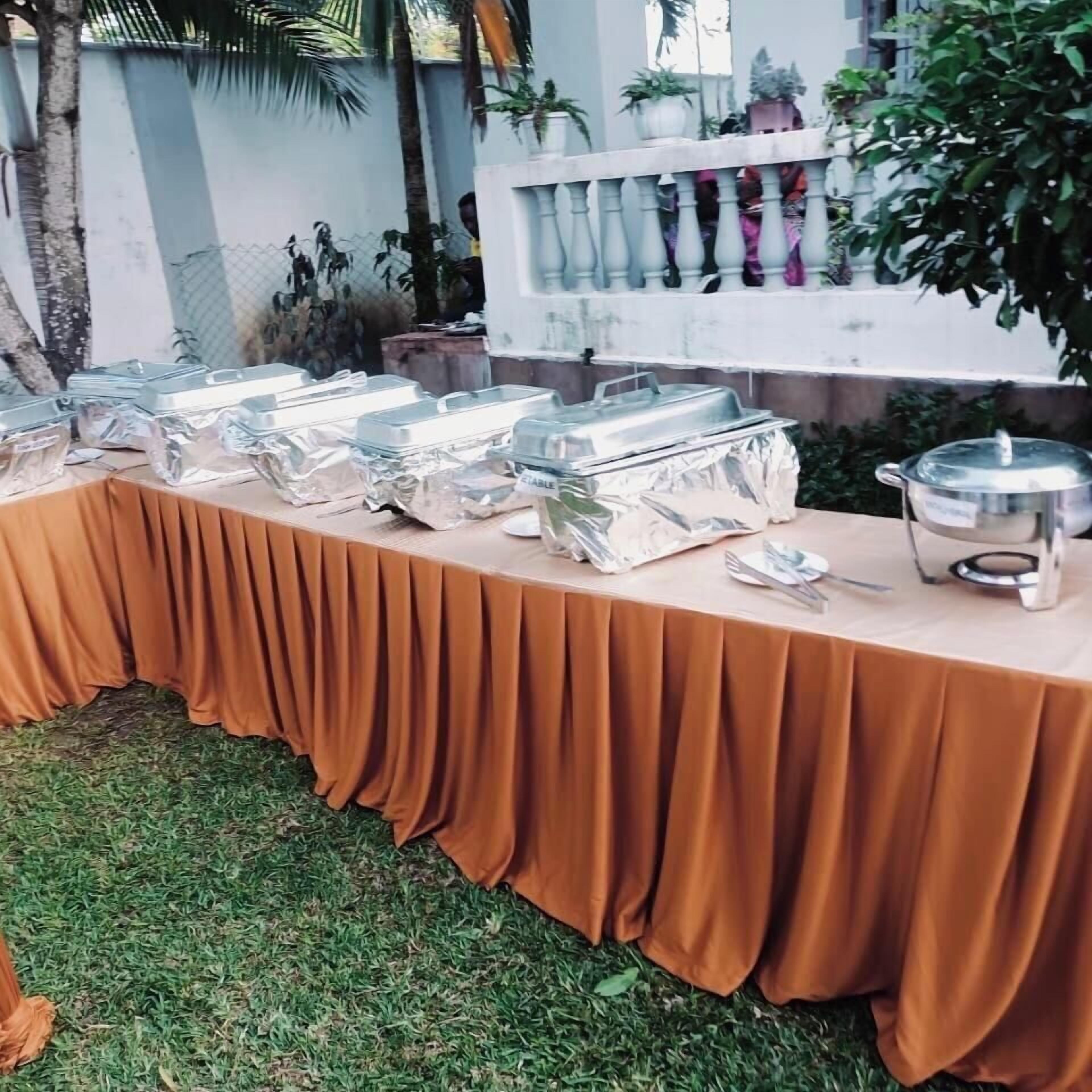 Une table de buffet avec des récipients contenant de la nourriture et des ustensiles de service.