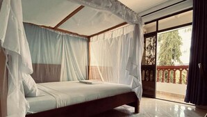 Un dormitorio con cama, ventilador de techo y balcón con vistas.