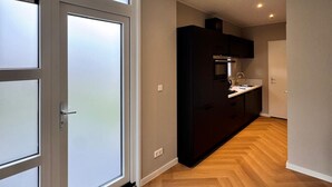 A modern kitchen with dark cabinetry, a countertop, and a built-in oven. - Lodge 65 | 6 persoons chalet in Zennewijnen (Zennewijnen)