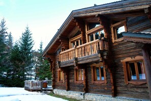A log cabin with a balcony, stone foundation, and large windows. - Chalet in La Tania Near Ski Slopes (Courchevel)