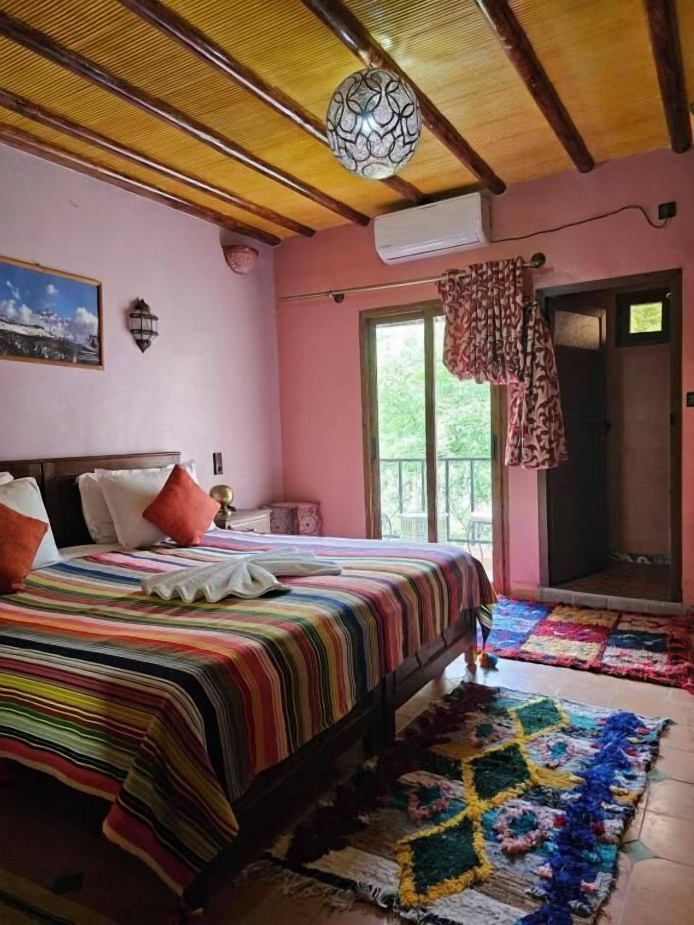 A bedroom with a bed, a window, a door, and a ceiling fan.