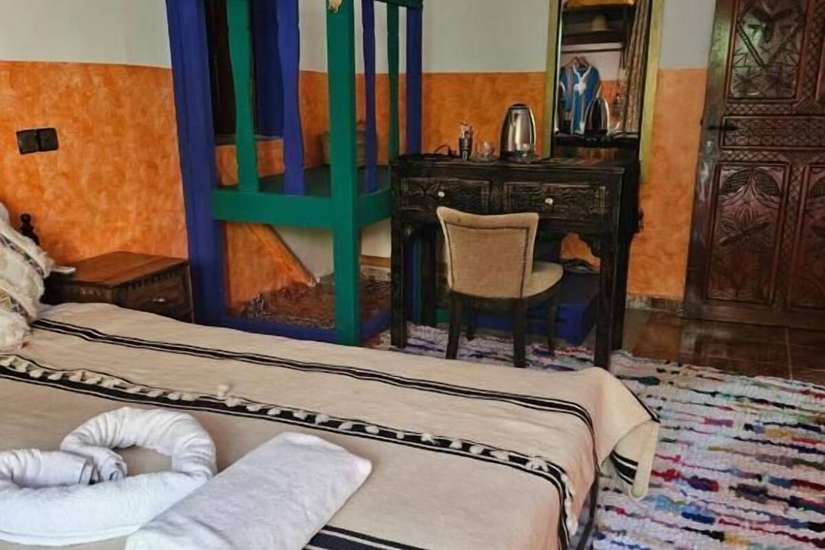 A room with a bed, a desk, a chair, a mirror, and a wardrobe.