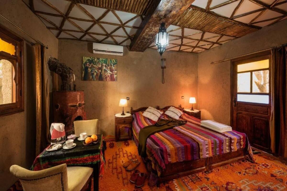 A room with a bed, a table with a lamp, a chair, and a window.