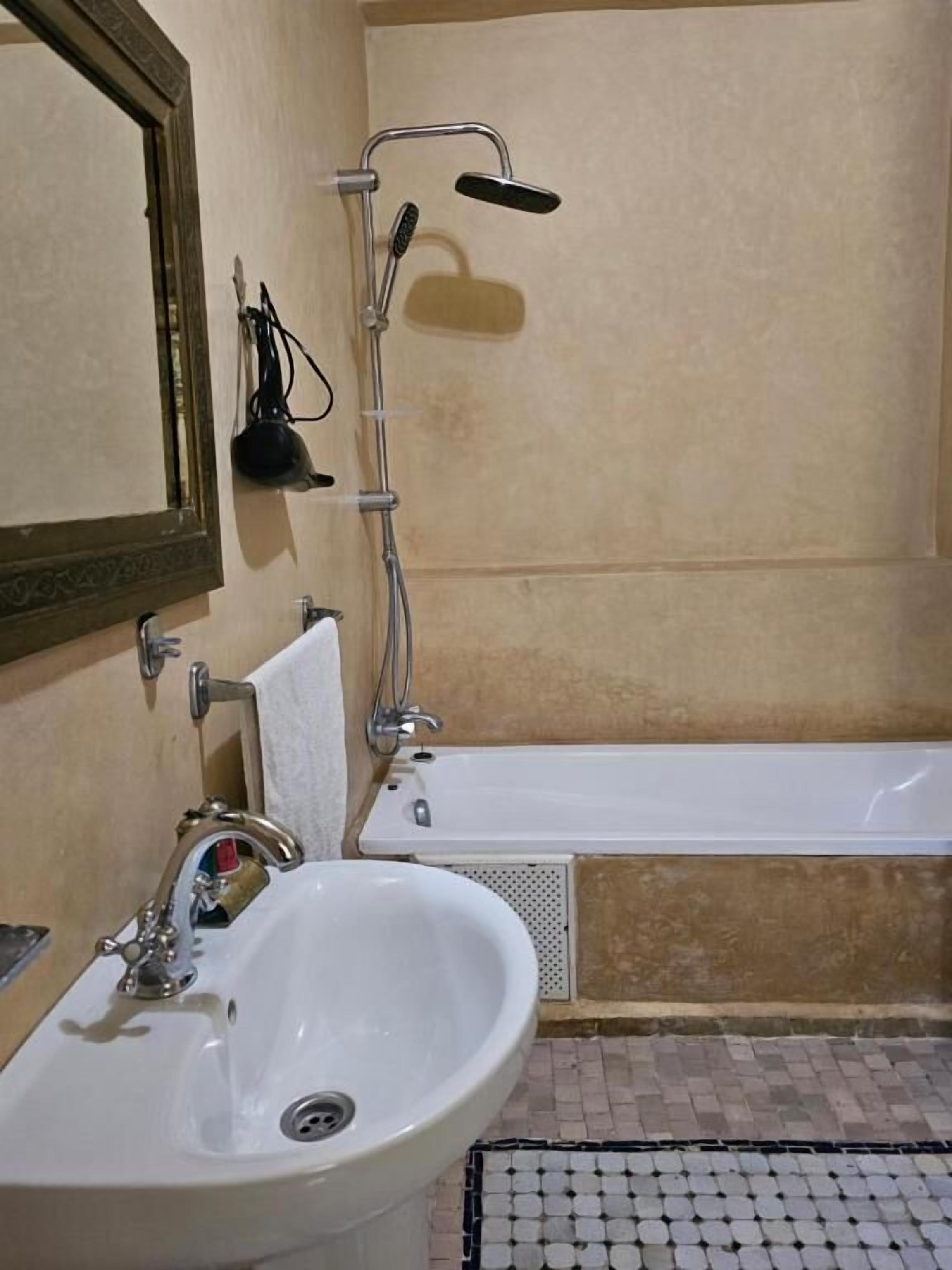 A bathroom with a sink, mirror, shower, and bathtub.