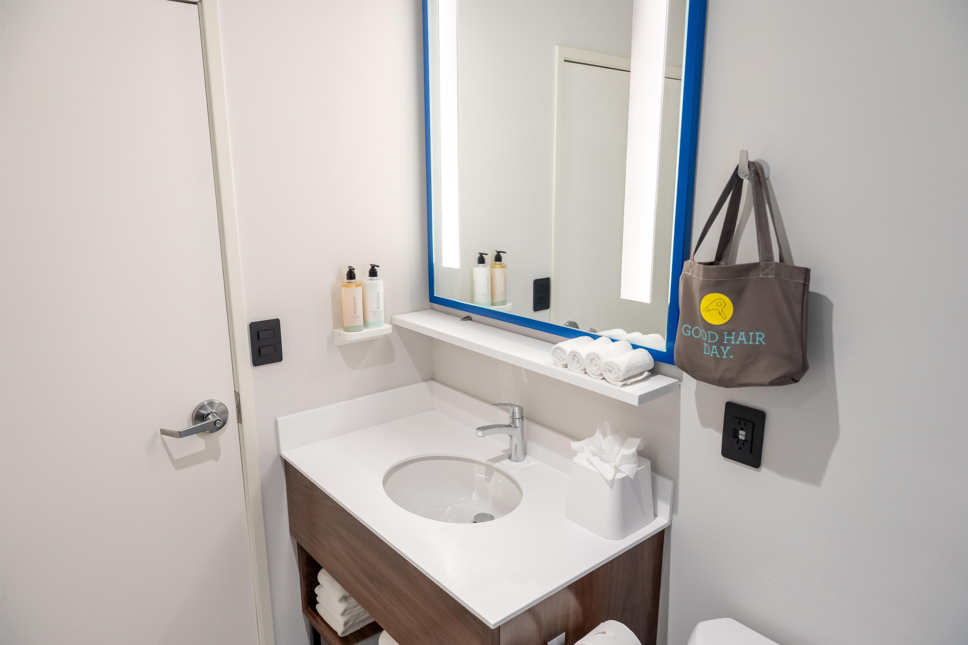 A modern bathroom with a white sink, a mirror with a blue frame, and a towel rack.