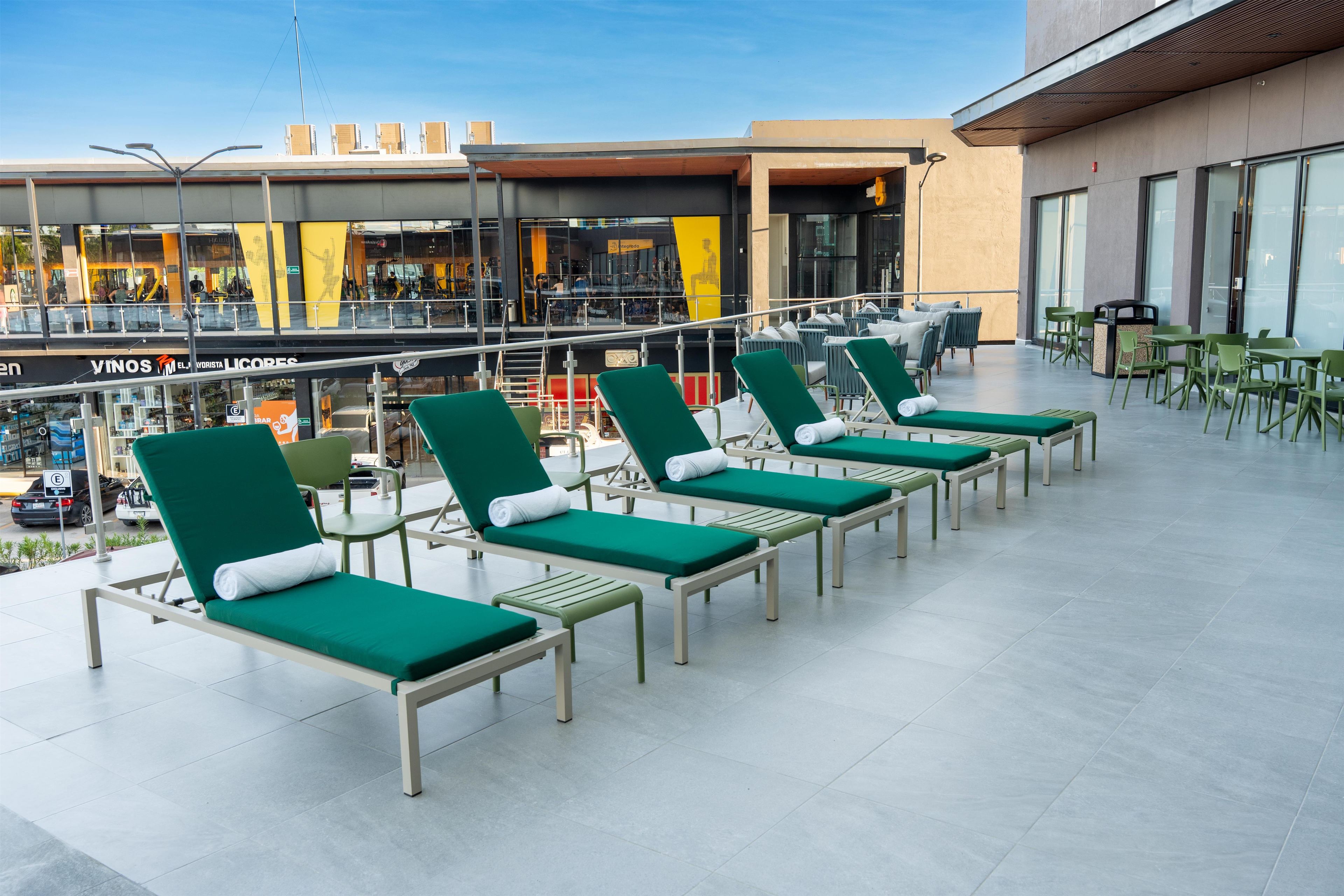 A rooftop terrace with green lounge chairs and a dining area.