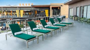 A rooftop terrace with green lounge chairs and a dining area.