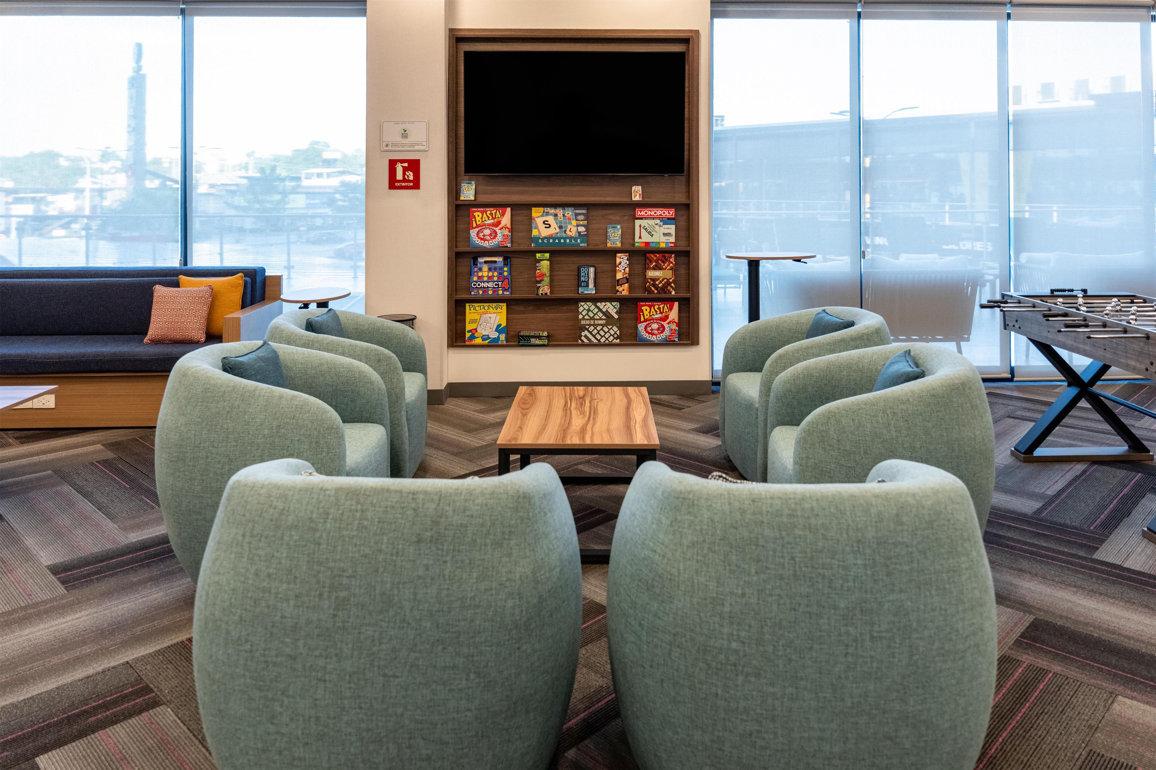 A modern lounge area with a sofa, chairs, a coffee table, and a board game shelf.