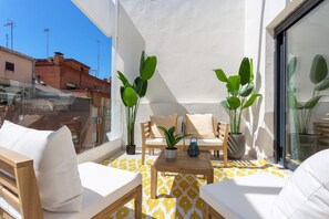 A balcony with a sofa, chairs, a table, and potted plants. - Genteel Home Zabaleta (Madrid)