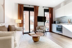 Una sala de estar moderna con un sofá, una mesa de centro y un televisor montado en la pared.