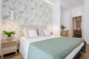A modern bedroom with a large bed, a nightstand with a plant, a mirror, and a wooden chair. - Genteel Home Zabaleta (Madrid)
