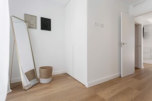 Ein Flur mit einem großen Spiegel, einem kleinen Korb und zwei gerahmten Kunstwerken an der Wand.