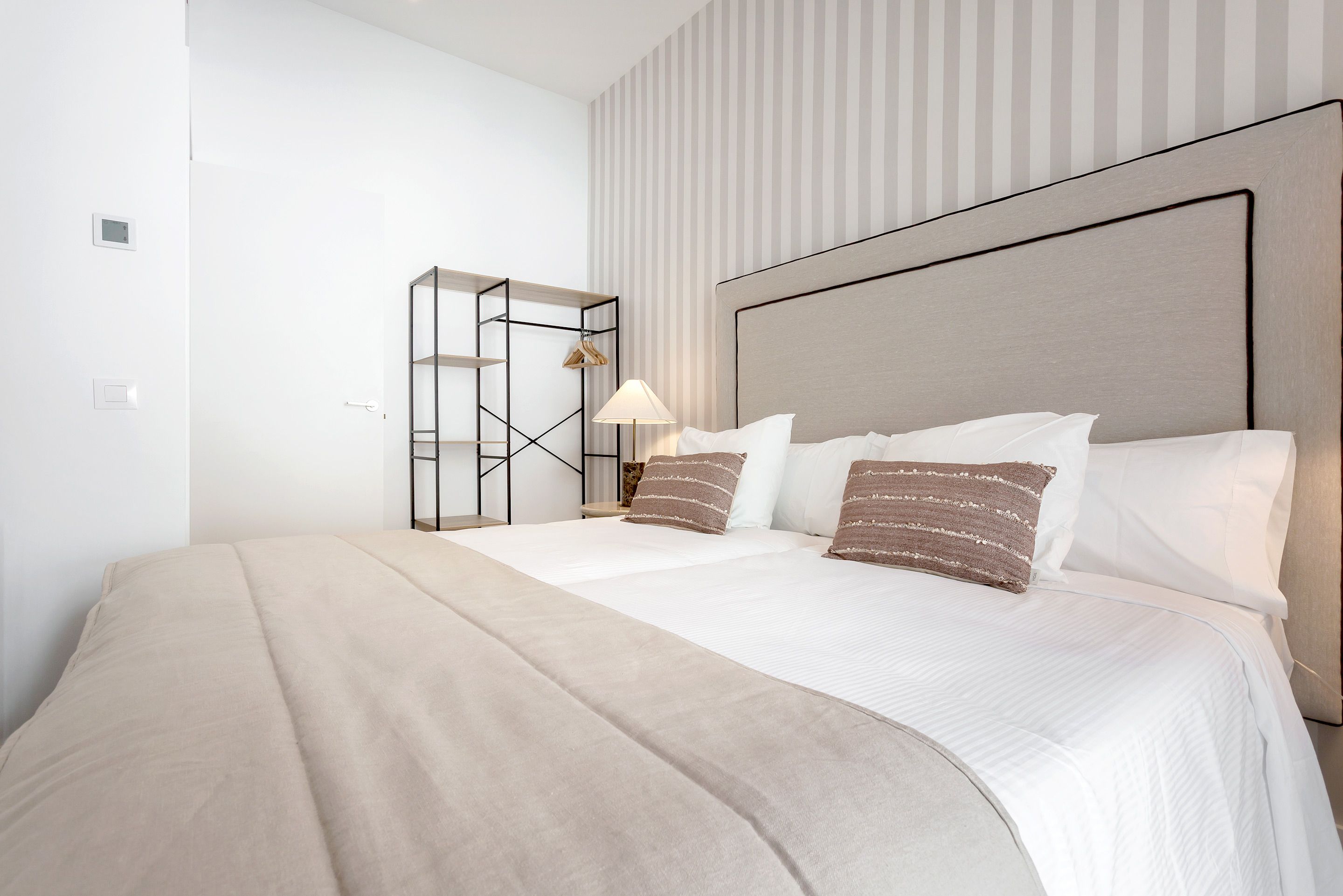 Una habitación de hotel con cama, mesita de noche, lámpara y armario.