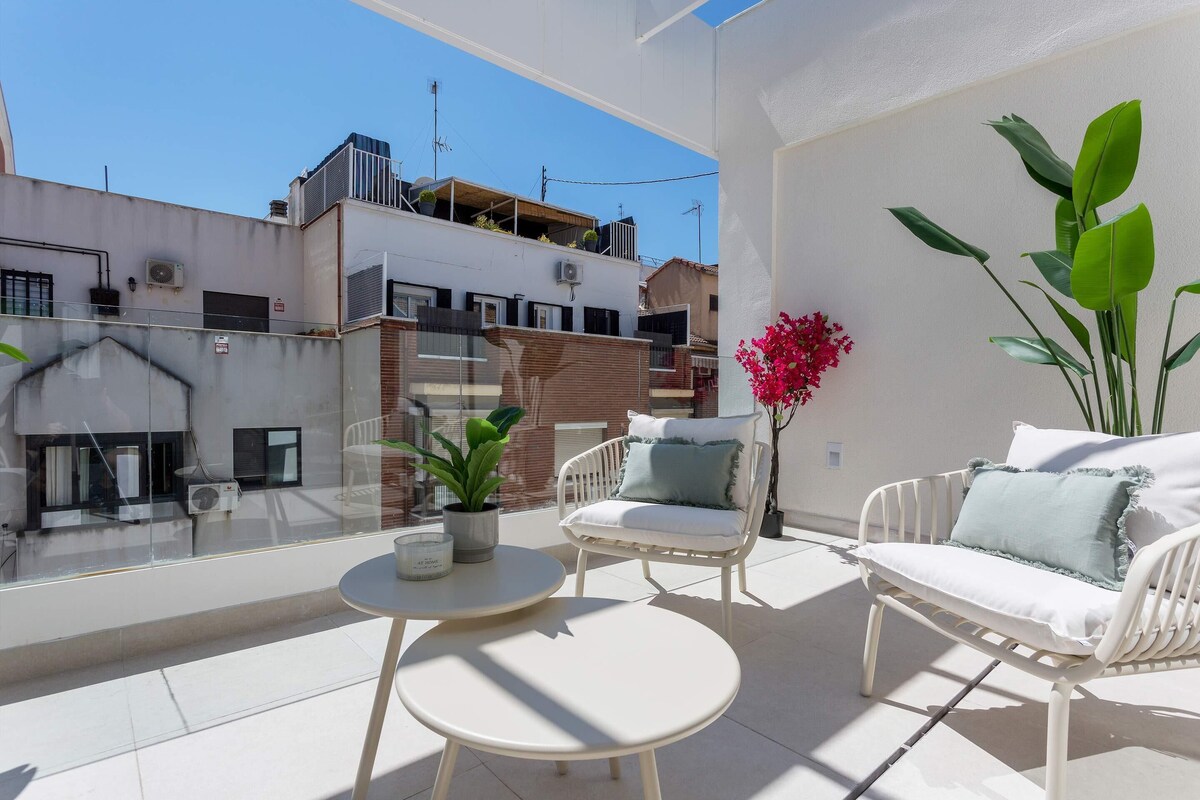 Ein Balkon mit einem weißen Stuhl, einem kleinen runden Tisch und einem Blumentopf.