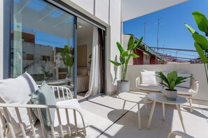 A balcony with white furniture, including a sofa and chairs, and a potted plant. - Genteel Home Zabaleta (Madrid)