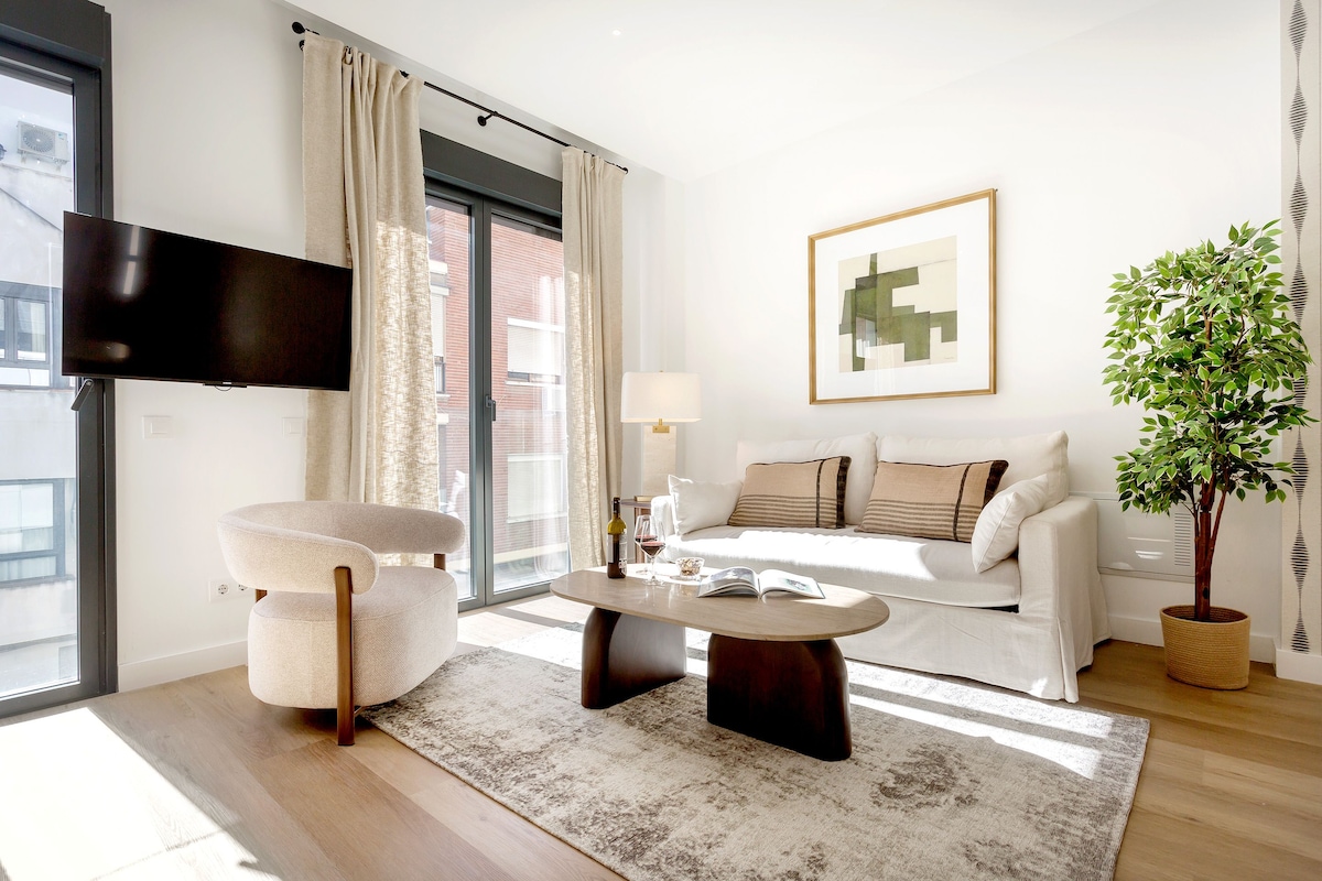 A modern living room with a flat-screen TV, a sofa, a coffee table, and a potted plant.
